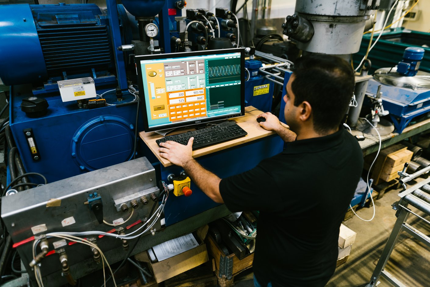 Eine Person steht vor einer Maschine und arbeitet an einem Monitor